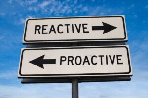 Reactive vs proactive. White two street signs with arrow on metal pole with word reactive and proactive. Directional road. Crossroads Road Sign, Two Arrow. Blue sky background.